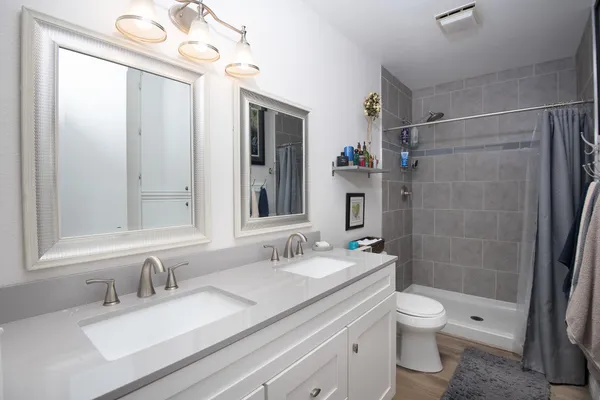 a bathroom with a granite countertop sink toilet a mirror a vanity and shower