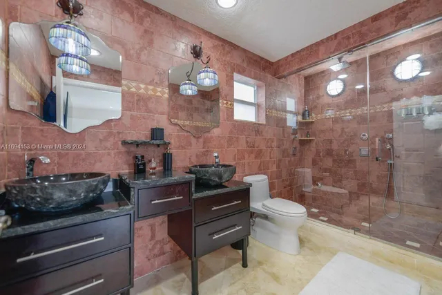 a bathroom with a granite countertop sink a toilet a mirror and shower