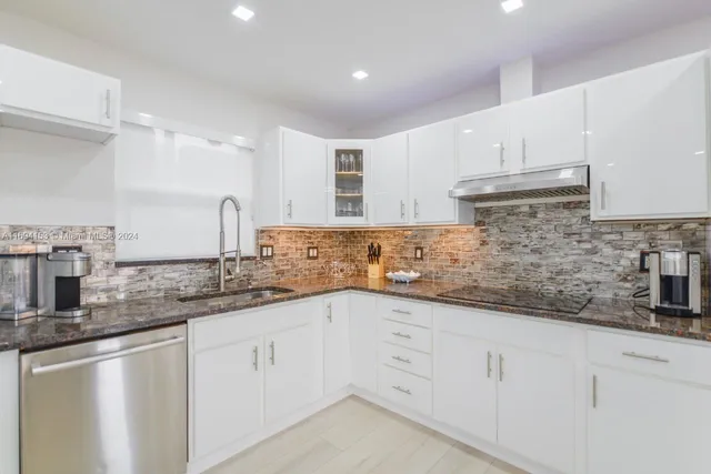 a kitchen with granite countertop white cabinets white appliances and a sink