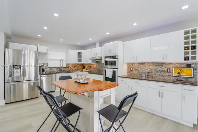 a kitchen with stainless steel appliances granite countertop a table chairs sink refrigerator and microwave