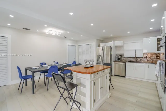 a kitchen with stainless steel appliances kitchen island granite countertop a table chairs sink and cabinets