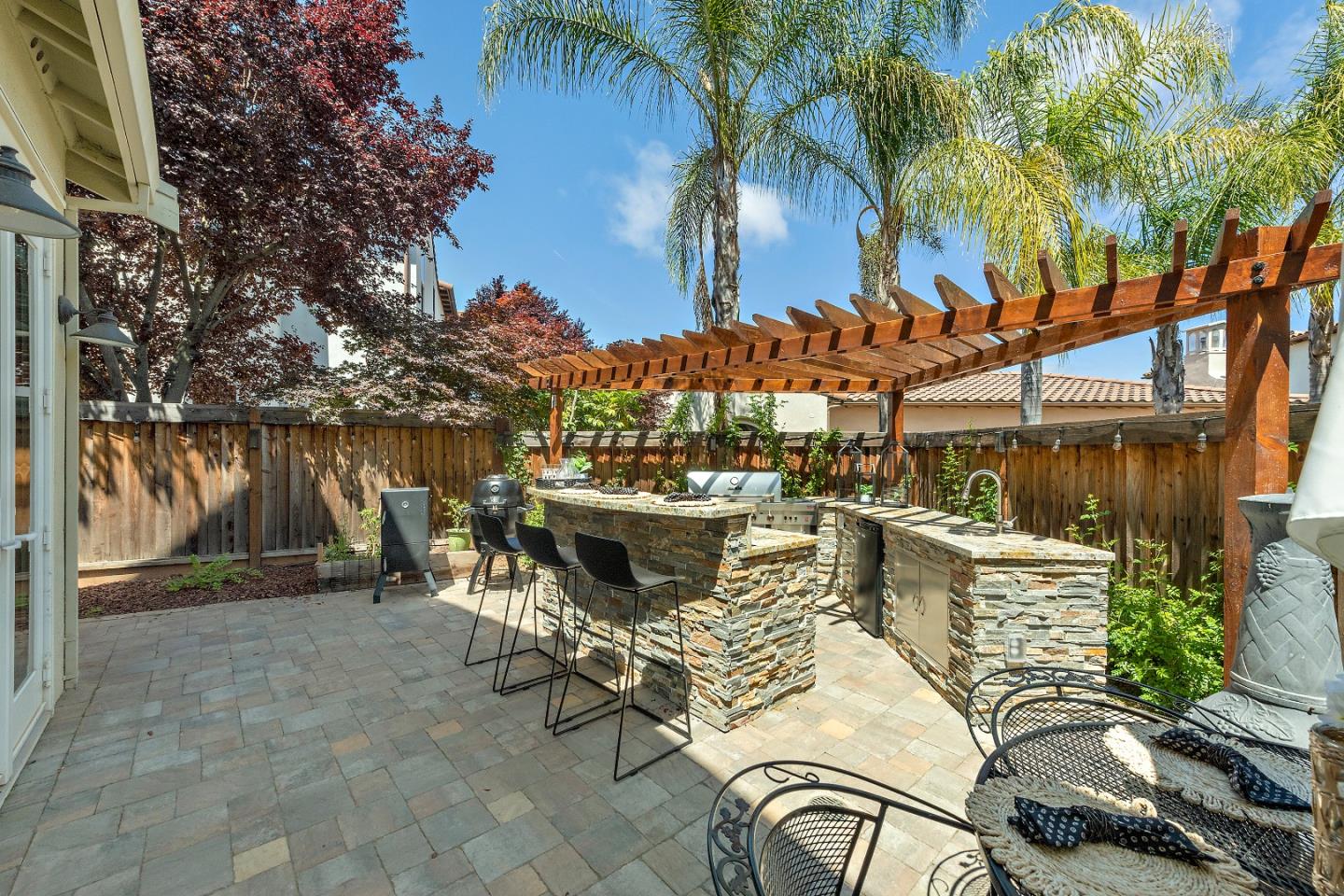 7581 Edinburgh Way Gilroy, CA 95020 - Photo 28 of 38 a view of a patio with couches table and chairs under an umbrella with palm trees
