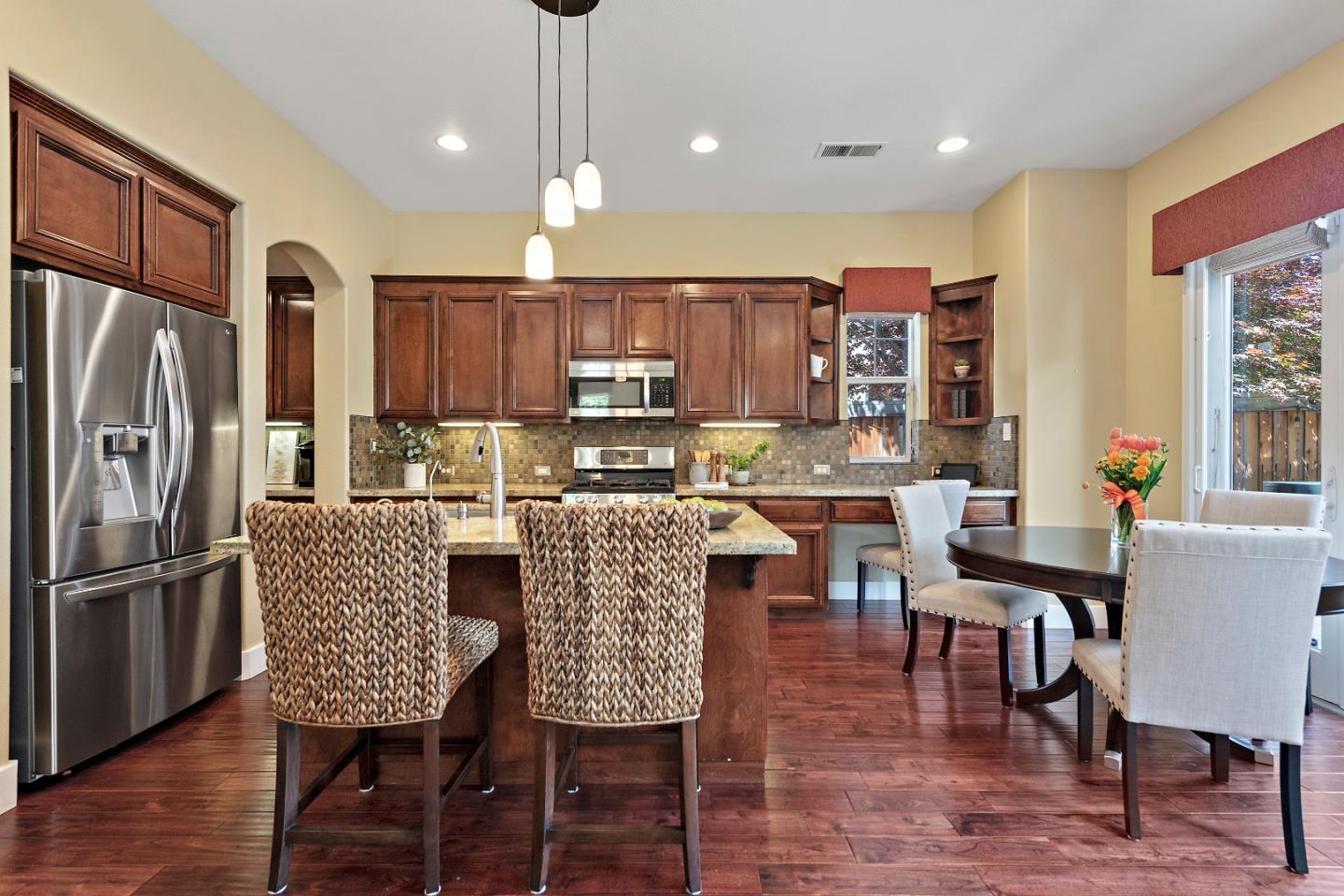 7581 Edinburgh Way Gilroy, CA 95020 - Photo 7 of 38 a kitchen with stainless steel appliances granite countertop a table chairs refrigerator and a window