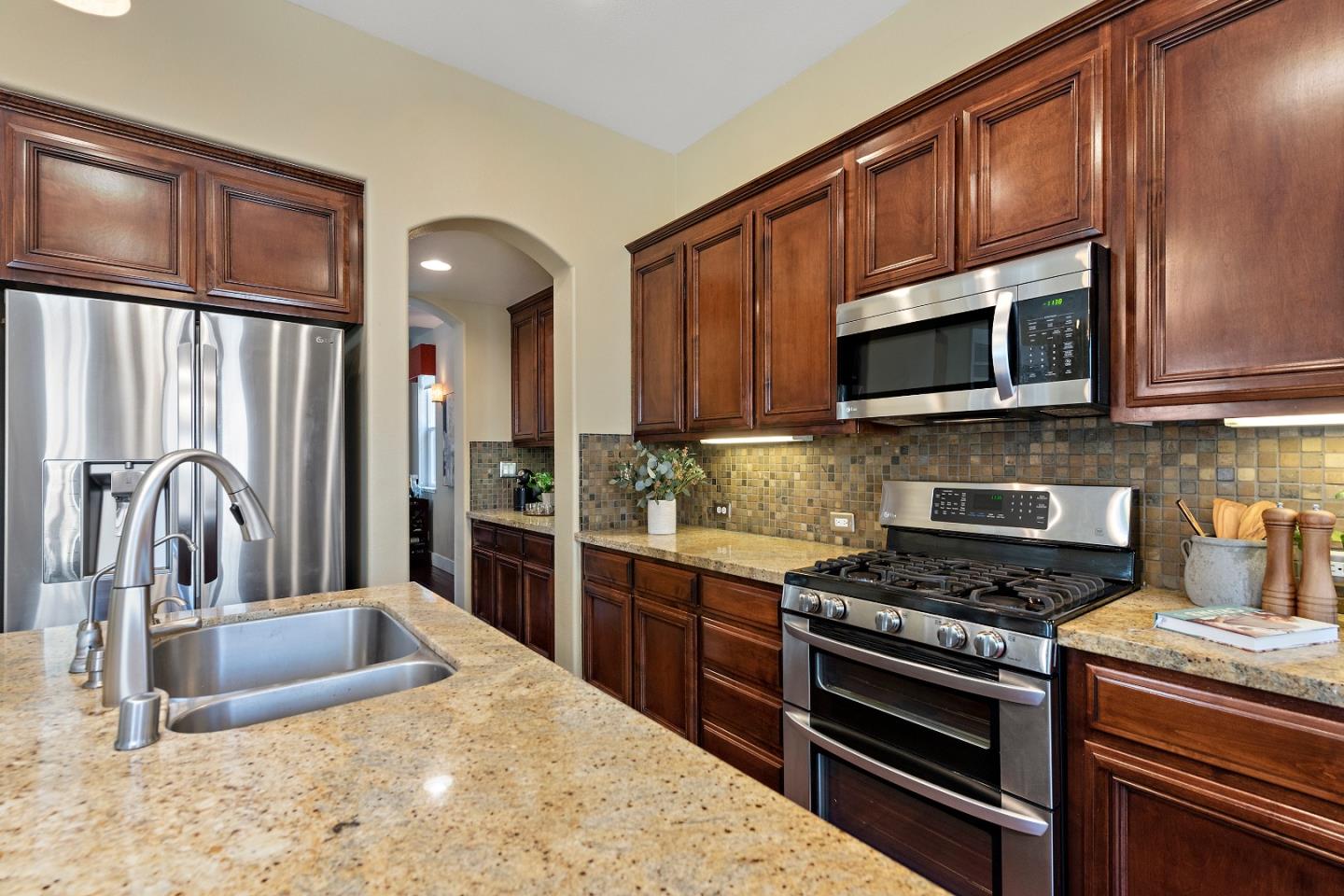 7581 Edinburgh Way Gilroy, CA 95020 - Photo 8 of 38 a kitchen with stainless steel appliances granite countertop a stove microwave and sink
