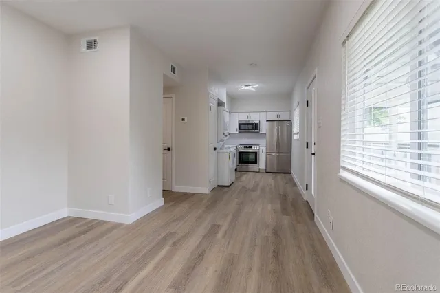 a view of a kitchen with a refrigerator a window and wooden floor