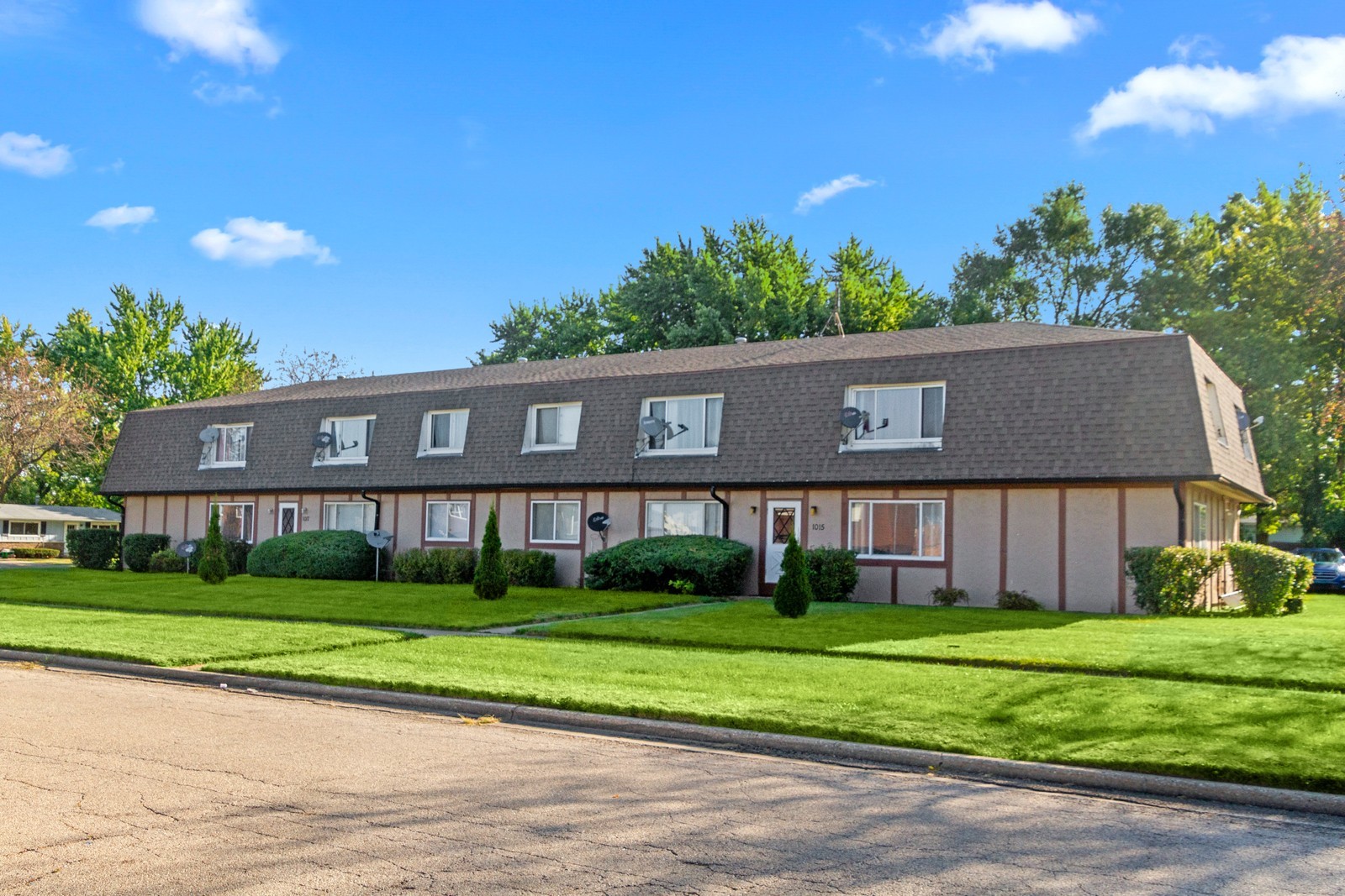 a view of house in front of a big yard with large trees