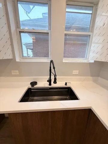 a large kitchen with stainless steel appliances a large counter top a sink and a chandelier