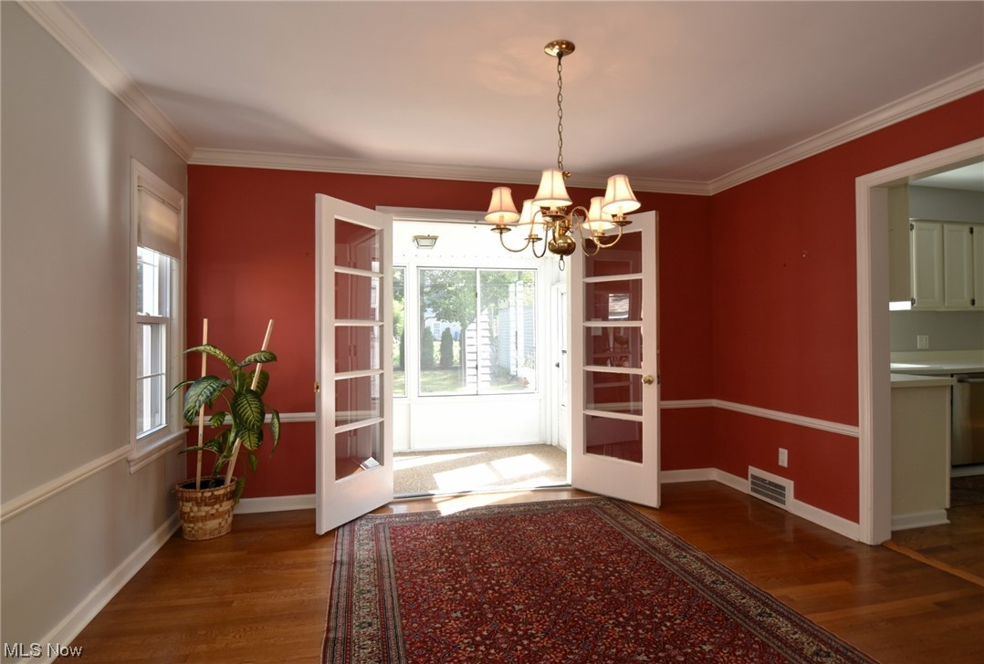 2295 Loyola Road Cleveland, OH 44118 - Photo 15 of 34 Doorway to outside featuring crown molding, a chandelier, andhardwood flooring