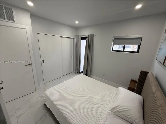 a bedroom with a bed and a refrigerator