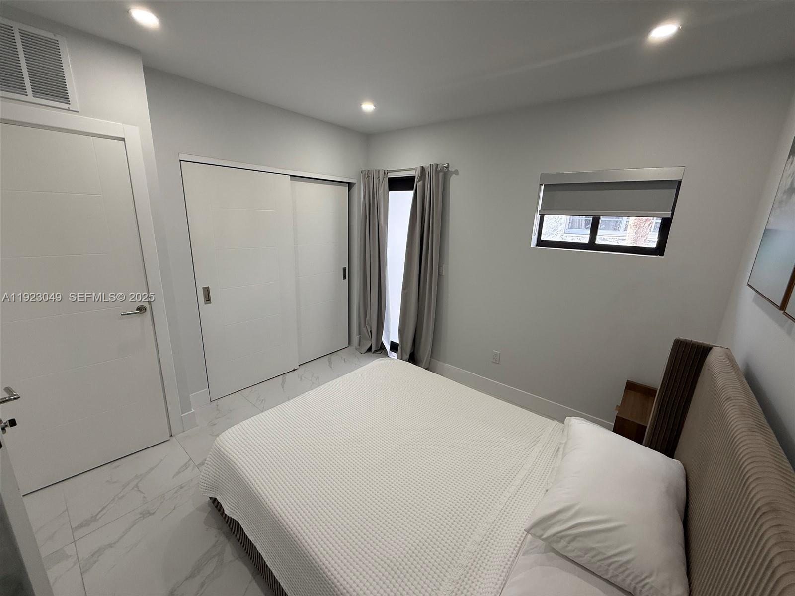 944 Jefferson Avenue, Unit 15 Miami Beach, FL 33139 - Photo 10 of 15 a bedroom with a bed and a refrigerator
