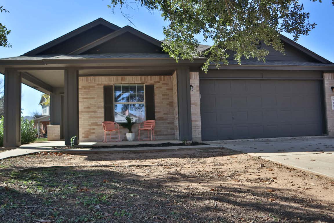 717 Blair Avenue Bastrop, TX 78602 - Photo 2 of 27 View of front facade featuring brick siding, a porch, driveway, a garage, and roof with shingles