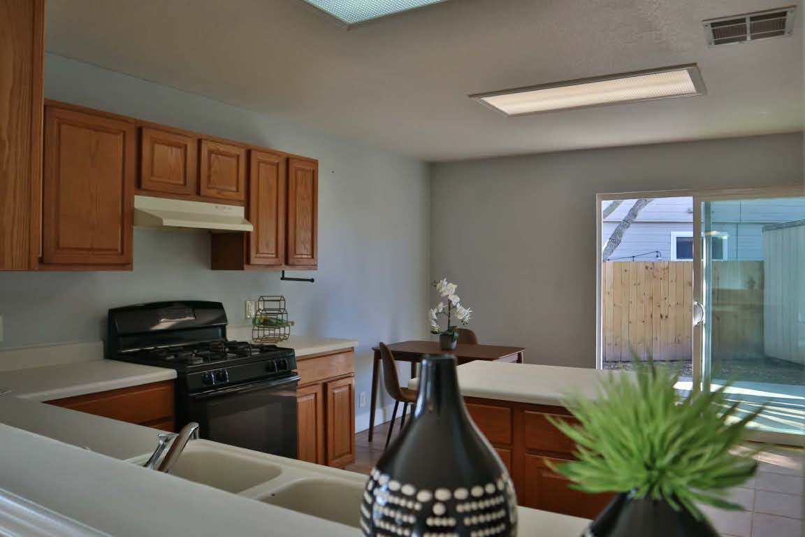 717 Blair Avenue Bastrop, TX 78602 - Photo 9 of 27 Kitchen with black gas stove, brown cabinets, light countertops, and under cabinet range hood