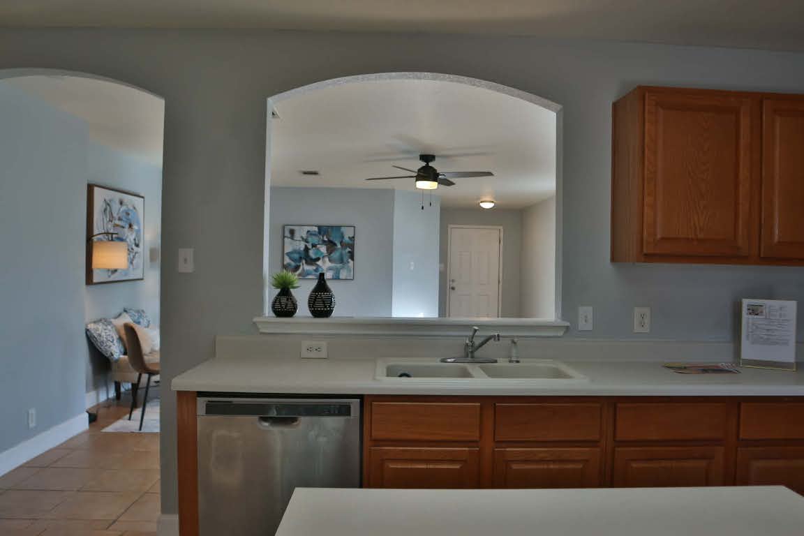 717 Blair Avenue Bastrop, TX 78602 - Photo 10 of 27 Kitchen featuring dishwasher, light countertops, light tile patterned floors, ceiling fan, and brown cabinetry