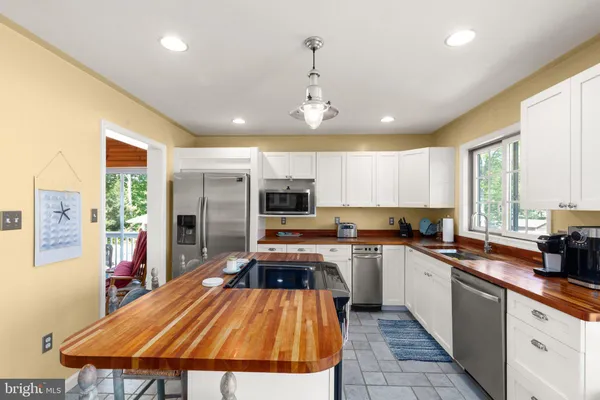a large kitchen with a large counter top space a sink stainless steel appliances and cabinets
