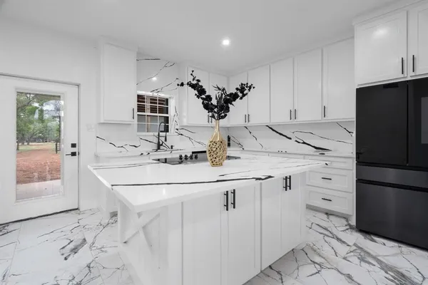 a kitchen with granite countertop white cabinets and refrigerator
