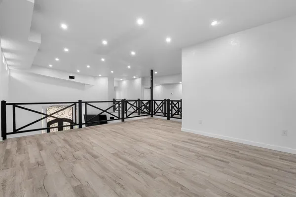 an empty room with wooden floor ceiling fan and windows