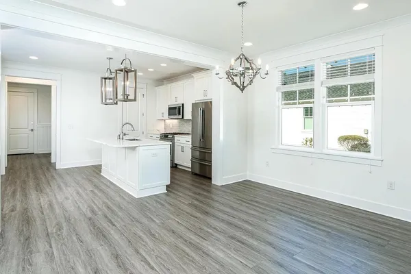 a view of a kitchen with stainless steel appliances wooden floor and chandelier