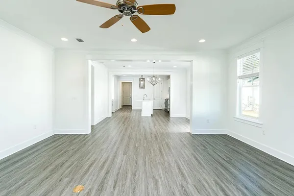 a view of empty room with wooden floor and fan