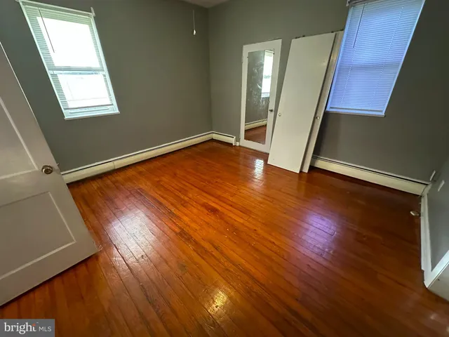 an empty room with wooden floor and entrance