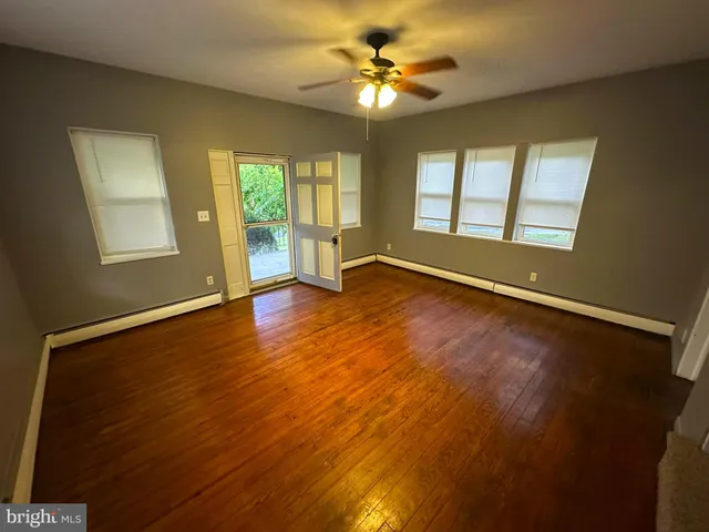 a view of an empty room with a window and wooden floor