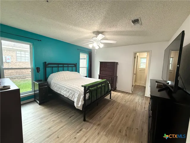 a bedroom with a bed a flat tv screen and dresser