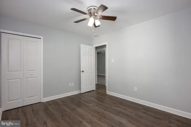 a view of an empty room with window a ceiling fan and wooden floor