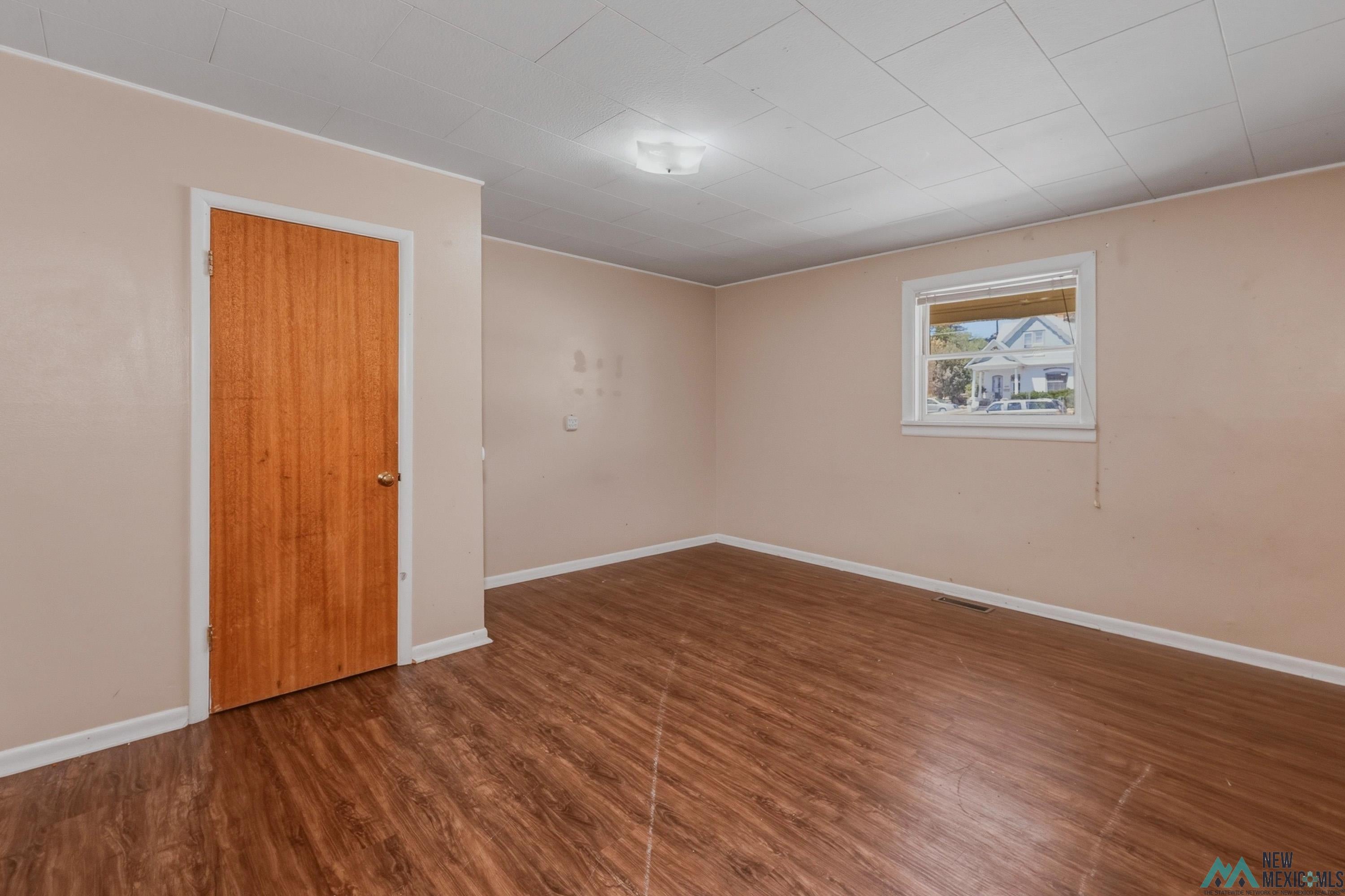 533 South 2nd Street Raton, NM 87740 - Photo 17 of 43 Room featuring wood-finish flooring, a neutral wall color, and a single window with blinds