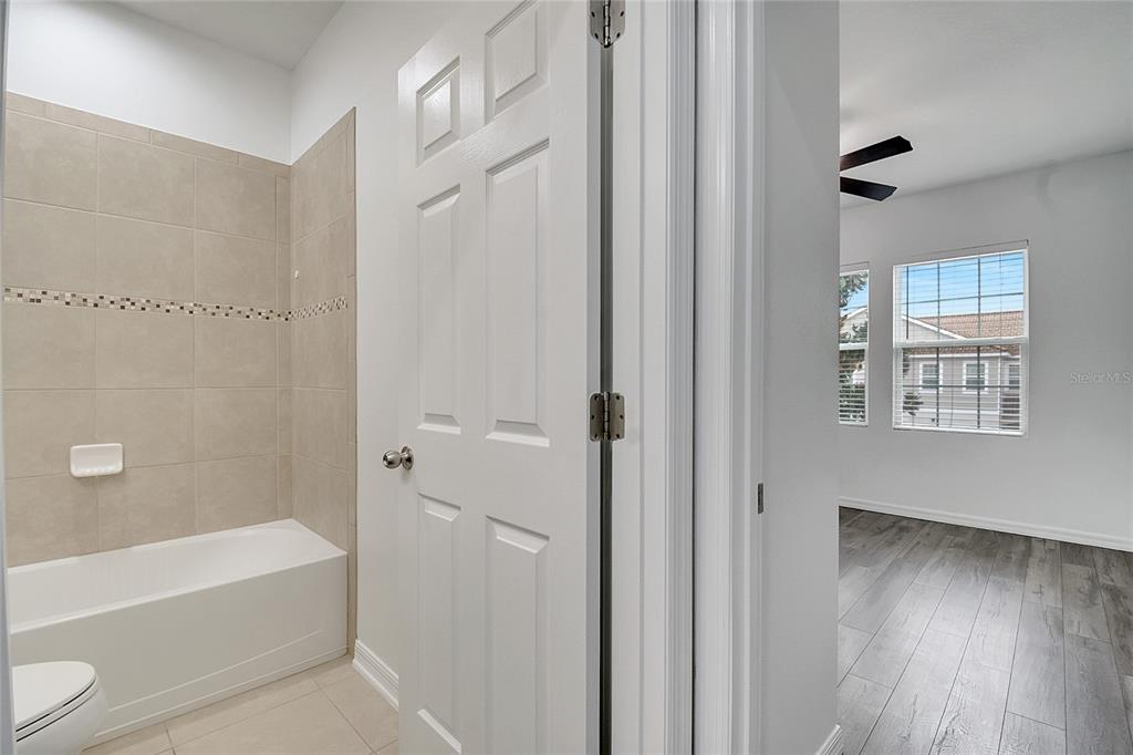 9161 Shepton Street Orlando, FL 32825 - Photo 38 of 62 a bathroom with a bathtub a window and a shower