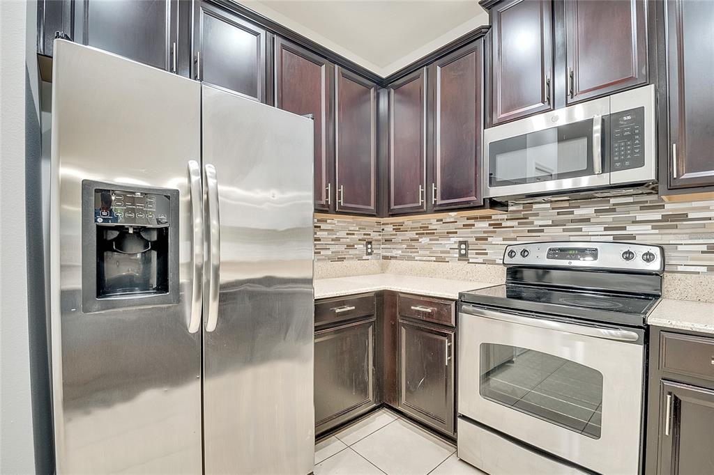 9161 Shepton Street Orlando, FL 32825 - Photo 10 of 62 a kitchen with stainless steel appliances granite countertop a stove a sink and a refrigerator