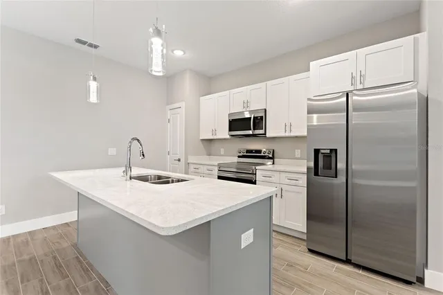 a kitchen with a sink a refrigerator a microwave and cabinets