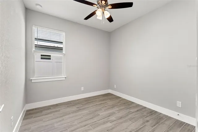 a view of an empty room with a window and wooden floor