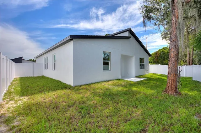 a backyard of a house with plants and large tree