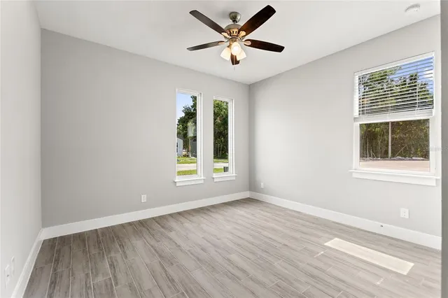 a view of an empty room with wooden floor and a window