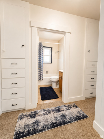 1766 Kenilworth Road Spring Glen, UT 84526 - Photo 9 of 24 Built-in white cabinetry with black hardware, tan carpet, and a bathroom featuring a window, white bathtub, and wood-finish vanity