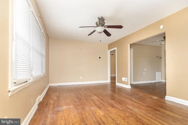 an empty room with wooden floor fan and windows