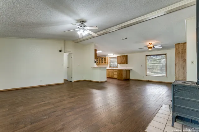 a view of an empty room with window and wooden floor