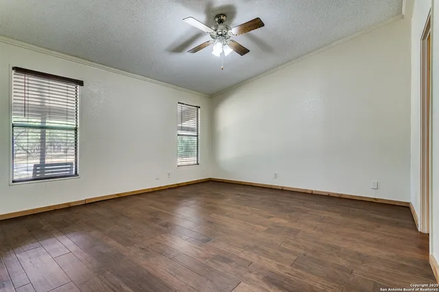 a view of an empty room with window and wooden floor