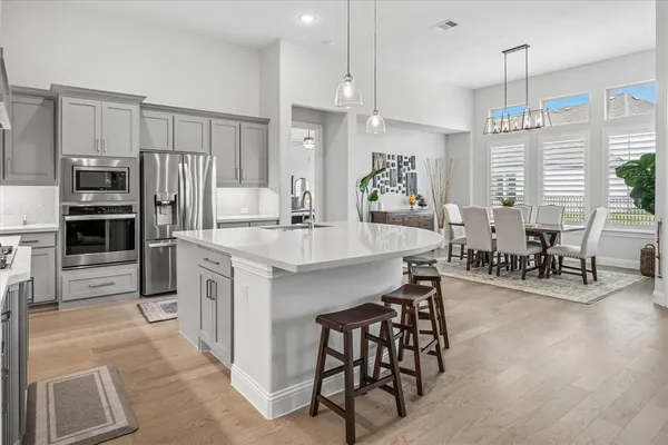 a kitchen with stainless steel appliances kitchen island granite countertop a table chairs and a refrigerator