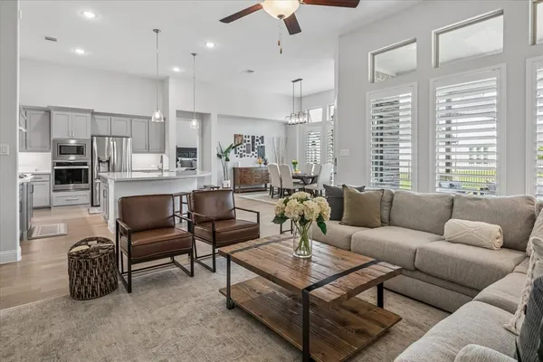 a living room with furniture kitchen view and a chandelier