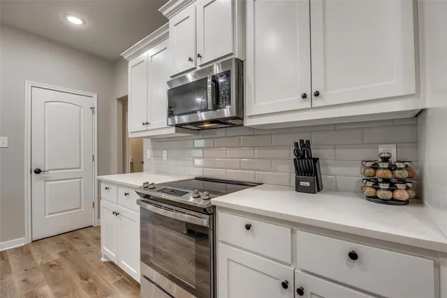 a kitchen with white cabinets and appliances