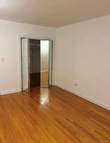 a view of an empty room with wooden floor & closet