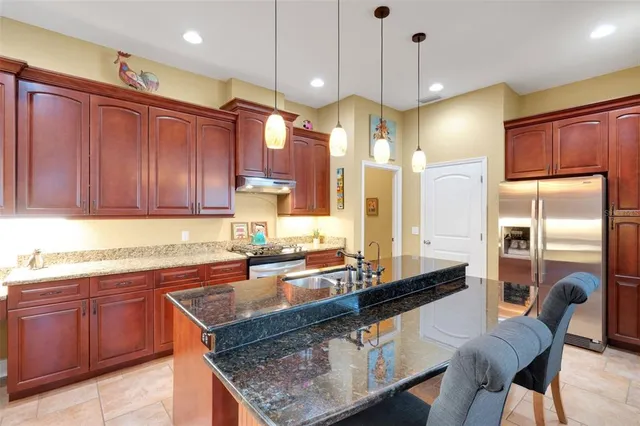 a kitchen with stainless steel appliances granite countertop a sink a stove and a refrigerator