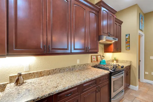 a kitchen with granite countertop stainless steel appliances wooden cabinets and a sink