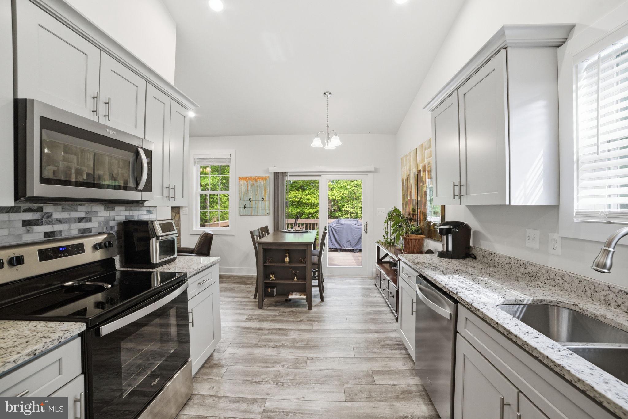 329 North Glebe Road Montross, VA 22520 - Photo 12 of 39 a kitchen with stainless steel appliances granite countertop a stove top oven a sink dishwasher a dining table and chairs with wooden floor
