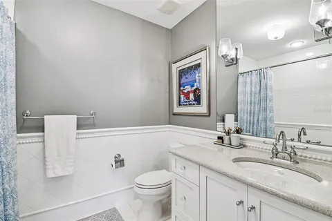 a view of a white house with a small yard and large tree