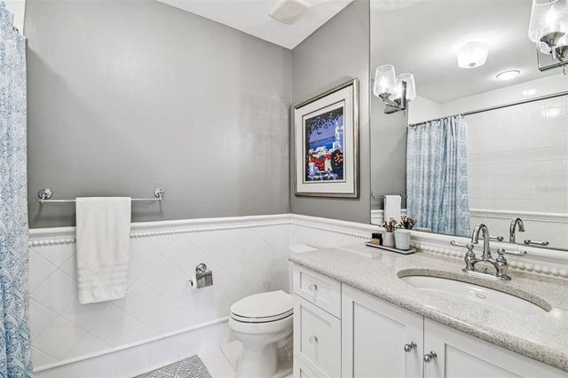 a view of a white house with a small yard and large tree