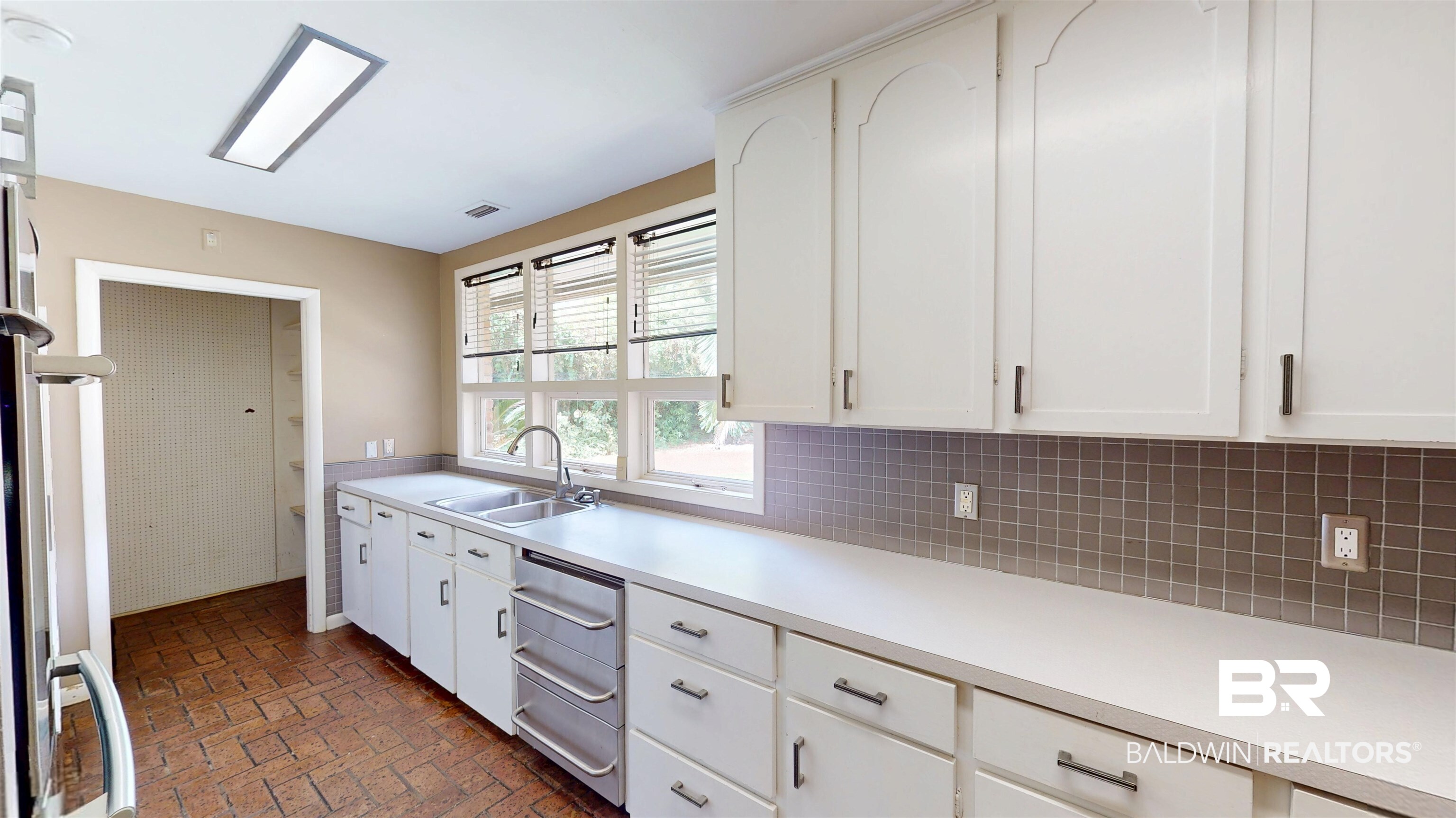 15 Spring Bank Road Mobile, AL 36608 - Photo 24 of 58 Kitchen with white cabinetry, brick flooring, light countertops, decorative backsplash, and dishwasher