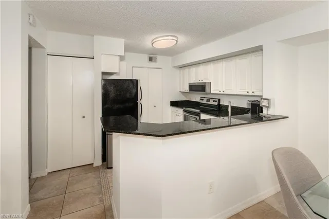 a kitchen with granite countertop white cabinets and black appliances