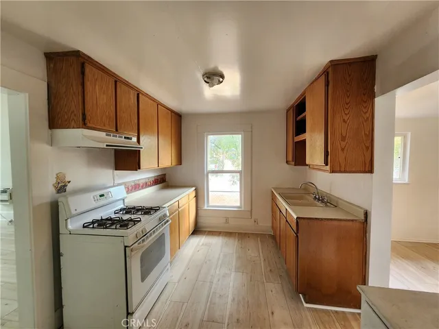 a kitchen with stainless steel appliances granite countertop a stove a sink dishwasher and a refrigerator with wooden floor