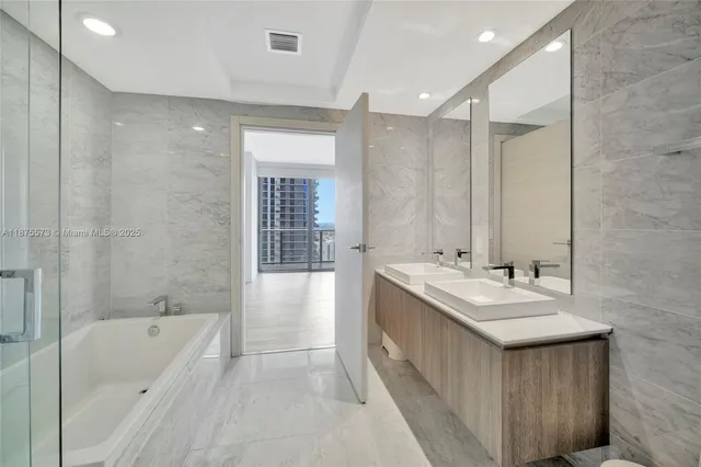 a bathroom with a bathtub a sink a mirror and a shower